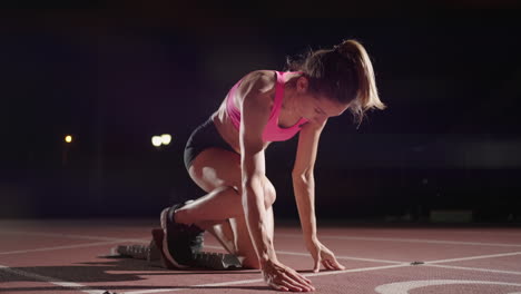 Mujer-Con-La-Mano-En-La-Pista-Mientras-Se-Agacha-En-La-Posición-Inicial-Al-Comienzo-De-Una-Carrera.-La-Atleta-Femenina-Se-Prepara-Y-Comienza.-Manos-Del-Corredor-Esperando-Al-Inicio-Frente-A-La-Línea-De-Inicio-En-El-Suelo.